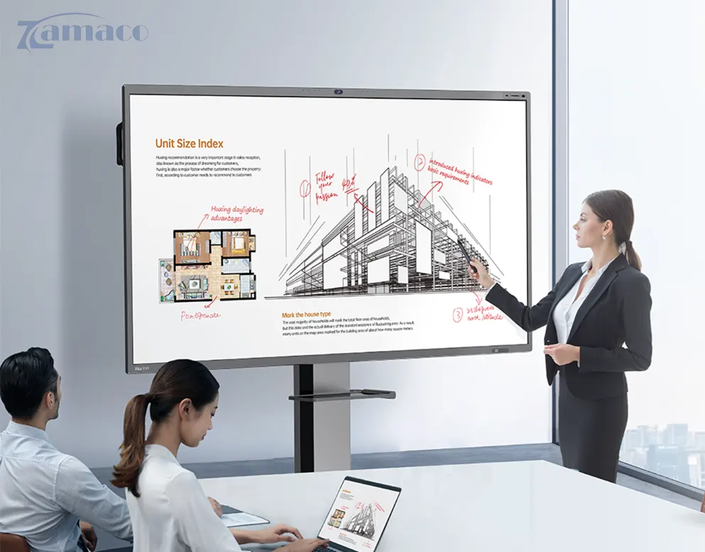 Màn hình tương tác Horion 65M3AGen2 - 65 inch Hình ảnh buổi họp văn phòng với màn hình tương tác Horion 65M3AGen2 đang hiển thị bản vẽ kiến trúc và ghi chú trực tiếp; một nữ nhân viên đang thuyết trình và tương tác với màn hình, trong khi hai đồng nghiệp theo dõi trên laptop.