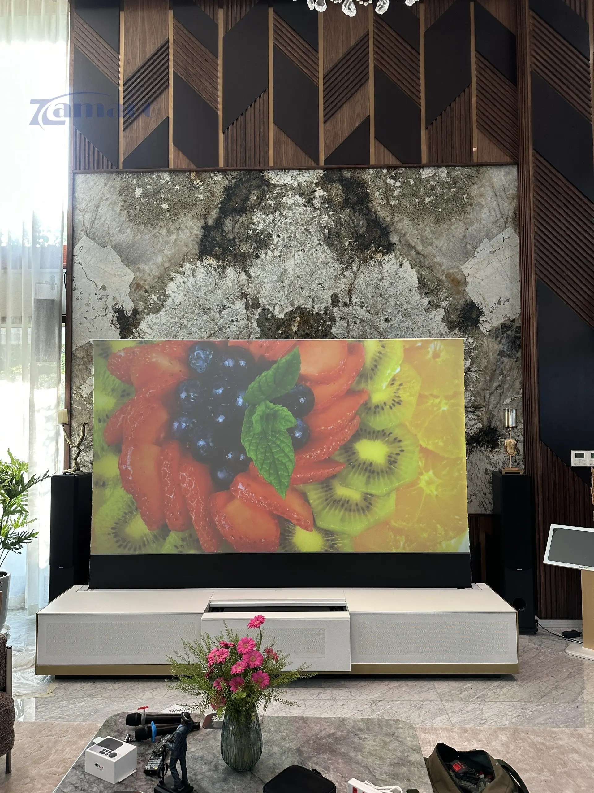 Hệ thống máy chiếu siêu gần Epson EH-LS800B được lắp đặt trong tủ TV Laser New York, trình chiếu hình ảnh 120 inch trên màn chiếu quang học Vividstorm để sàn trong không gian phòng khách hiện đại.