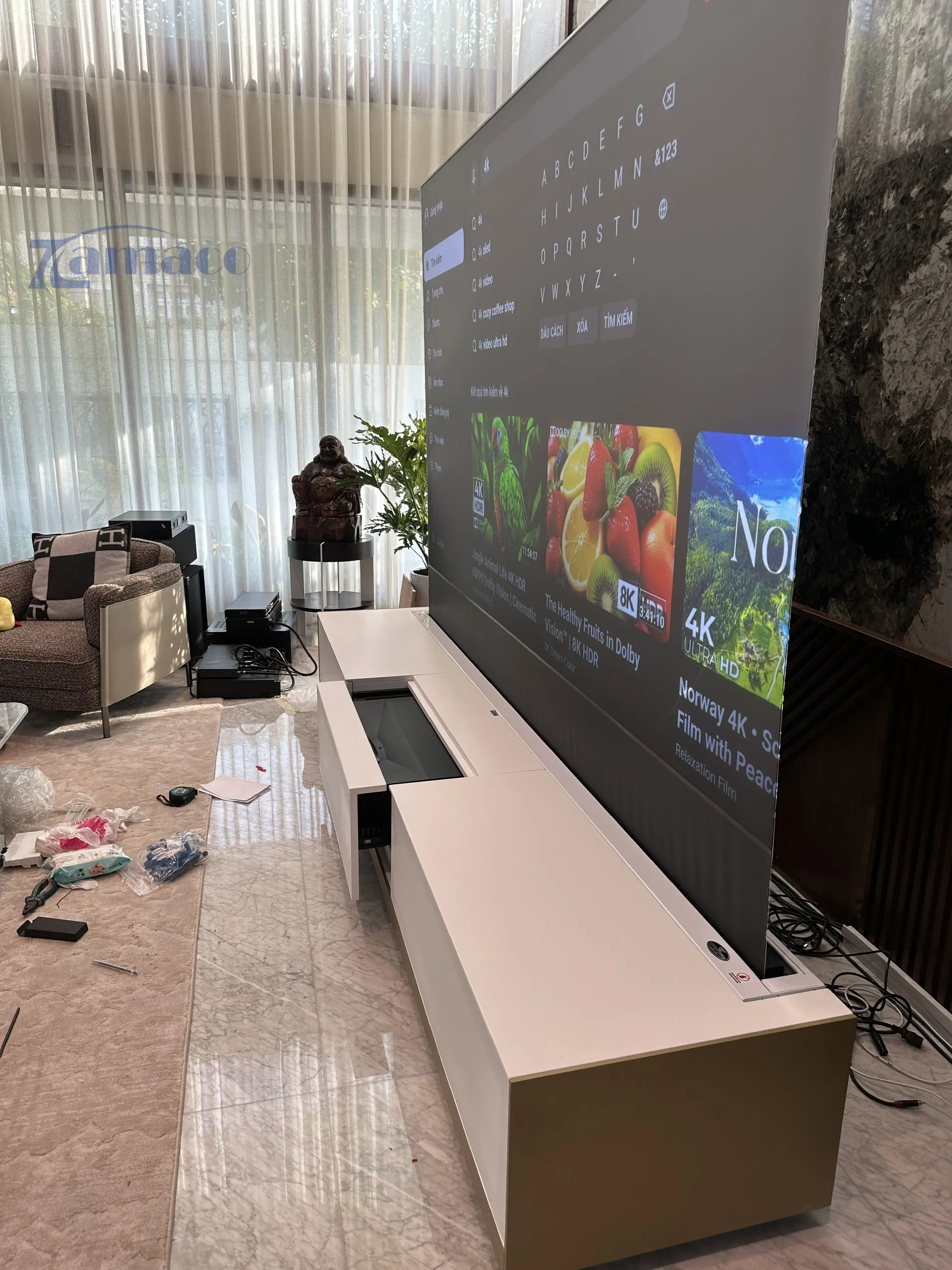 Hệ thống máy chiếu siêu gần Epson EH-LS800B được lắp đặt trong tủ TV Laser New York, trình chiếu hình ảnh 120 inch trên màn chiếu quang học Vividstorm để sàn trong không gian phòng khách hiện đại.